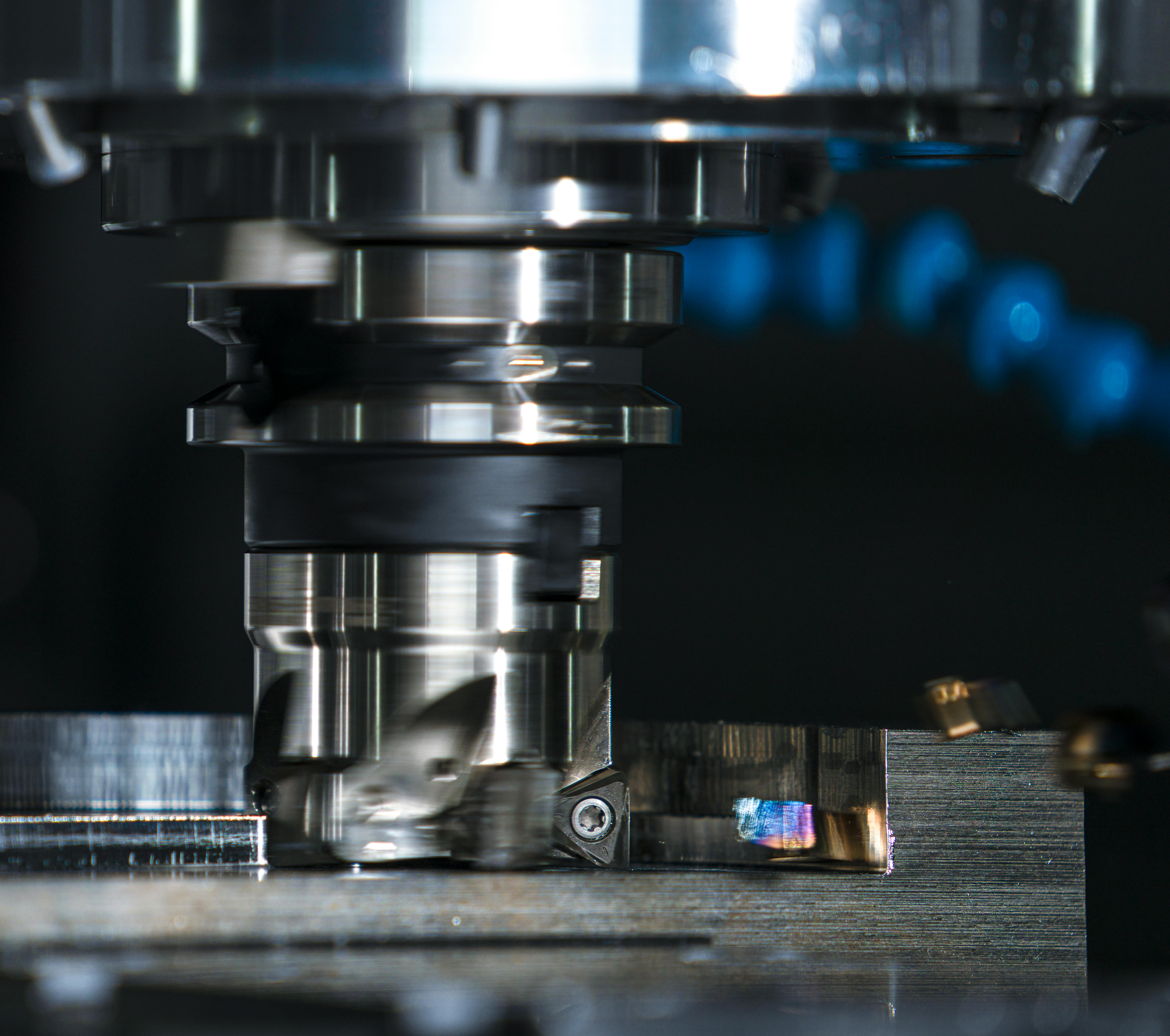 Primer plano de un cabezal de mecanizado trabajando sobre una pieza metálica, destacando la precisión y velocidad del proceso de corte en una máquina CNC
